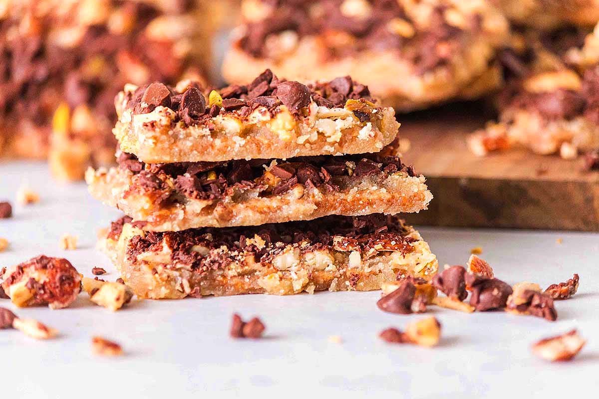 A stack of chocolate peanut butter bars, perfect for Christmas candy recipes, on a cutting board.