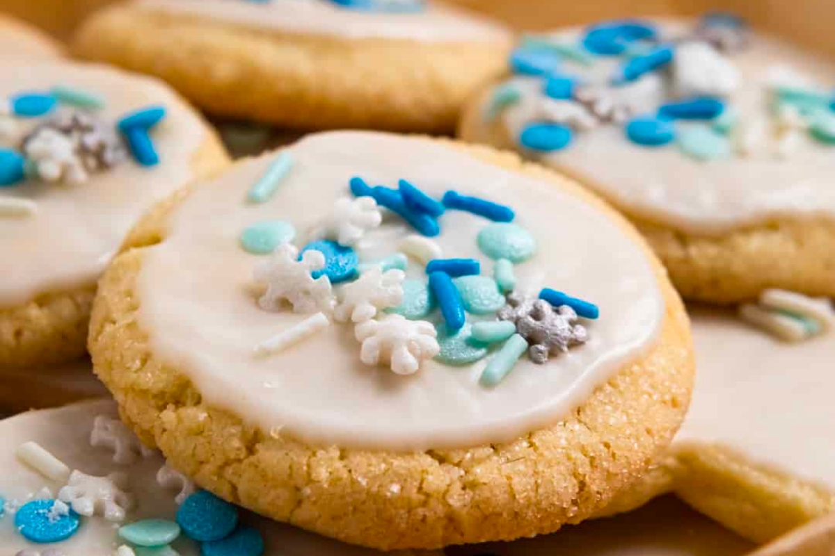 A box of Christmas sugar cookies with blue sprinkles and icing.