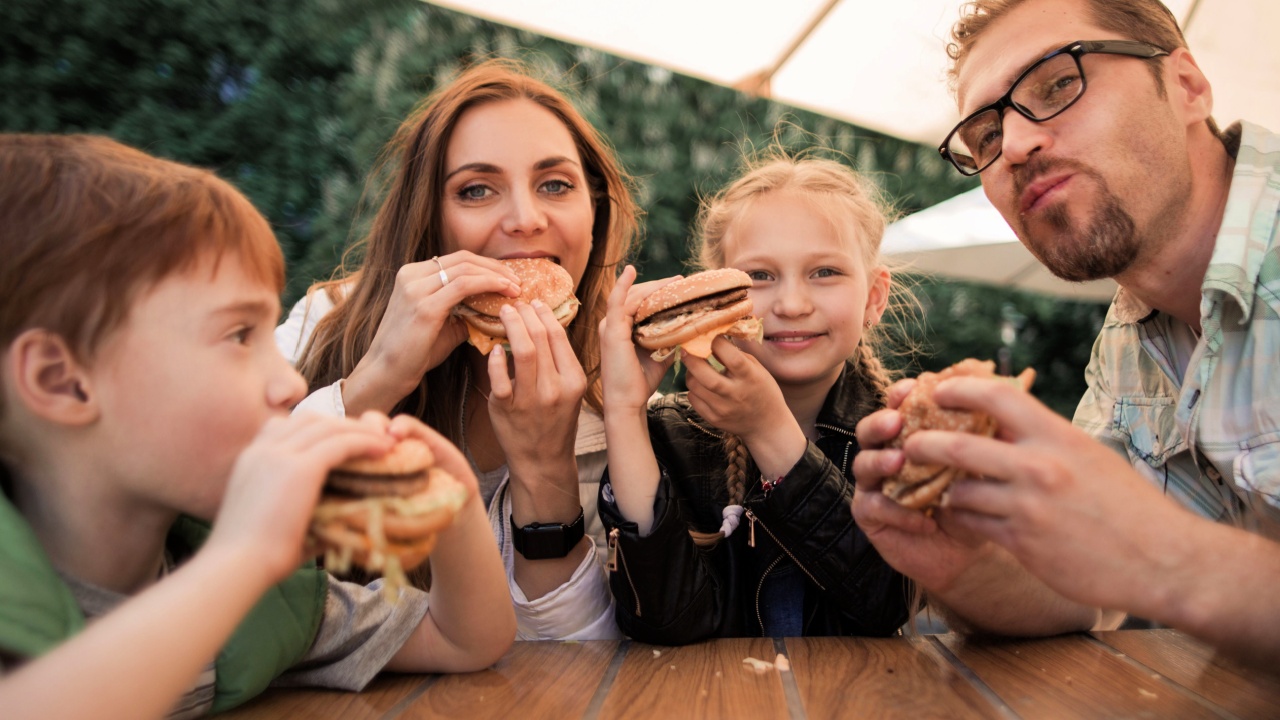 happy family eating burgers sitting at a table 