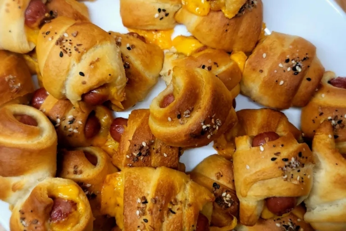 The easiest Game Day recipe - cheesy hot dog buns with cheese and sesame seeds on a plate.