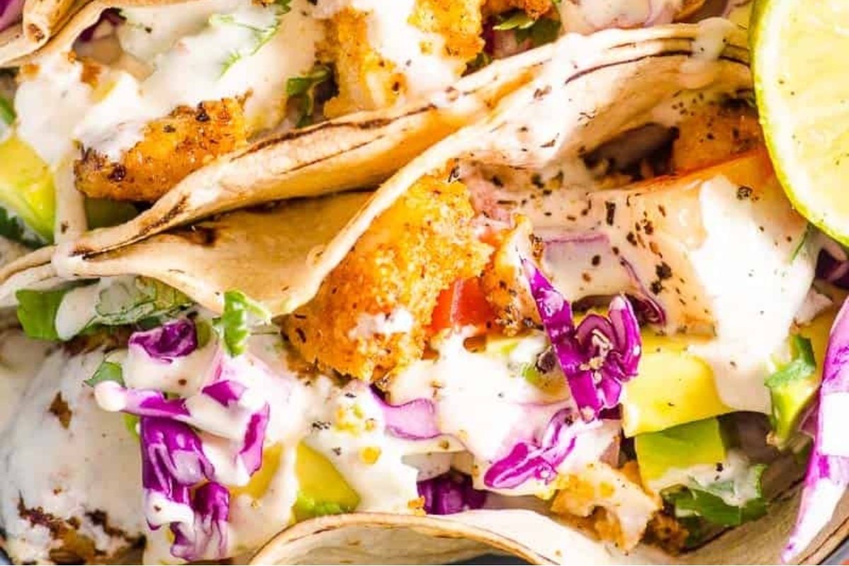 A plate of fish tacos with a lime wedge on top.