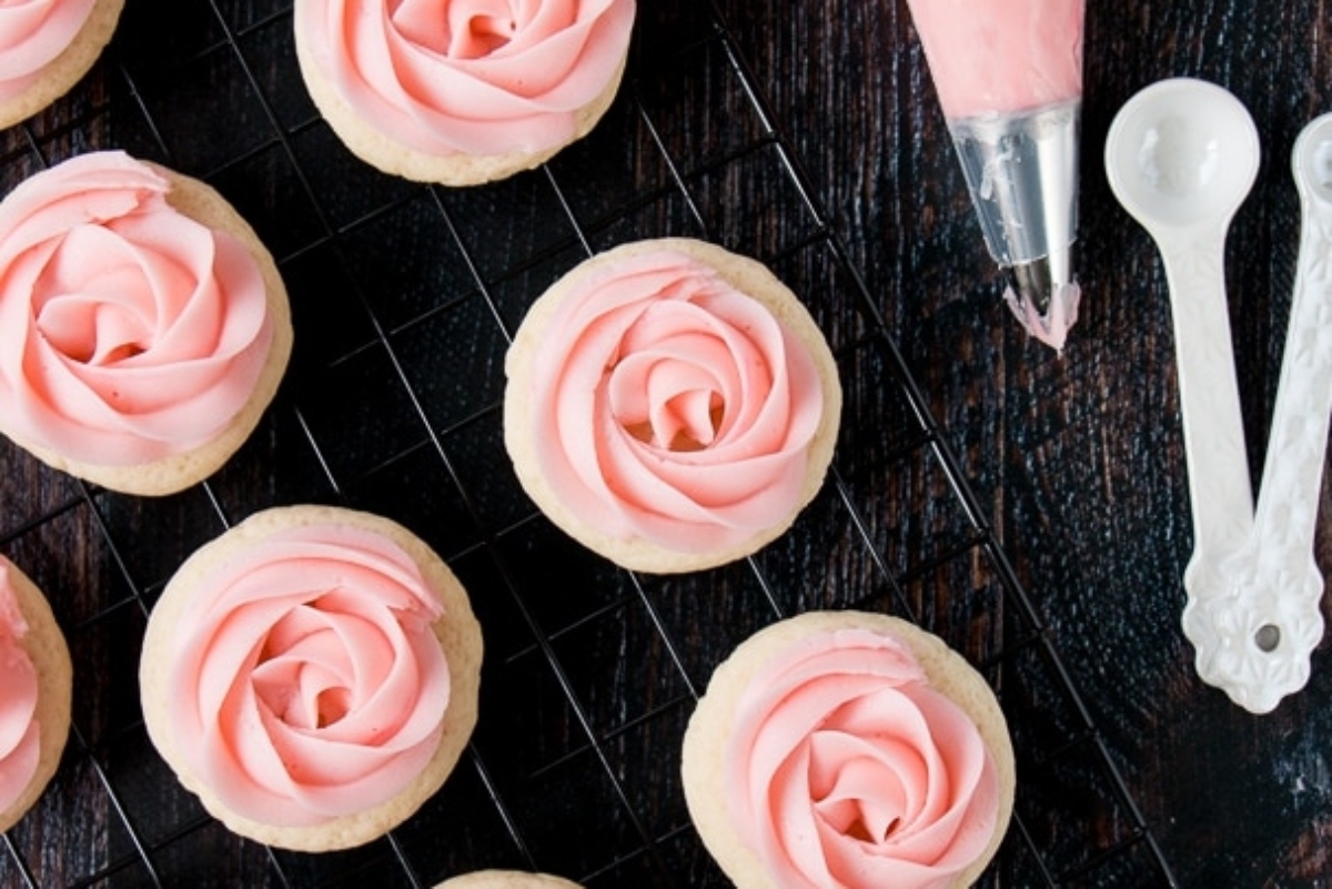 Valentine's Day sugar cookies with pink frosting resting on a cooling rack.