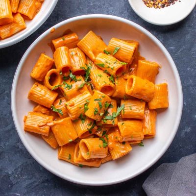 Gigi Hadid's easy pasta recipe features two bowls of pasta with sauce and herbs on a table.