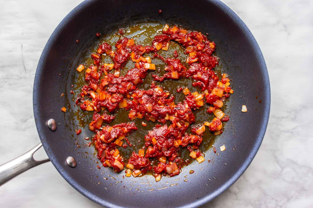 A fiery frying pan sizzling with red chilies, perfect for adding some heat to your favorite pasta recipe.