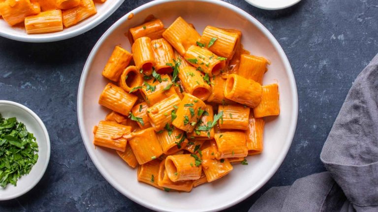 Gigi Hadid's pasta recipe featuring a bowl of delicious pasta with sauce and parsley on a table.