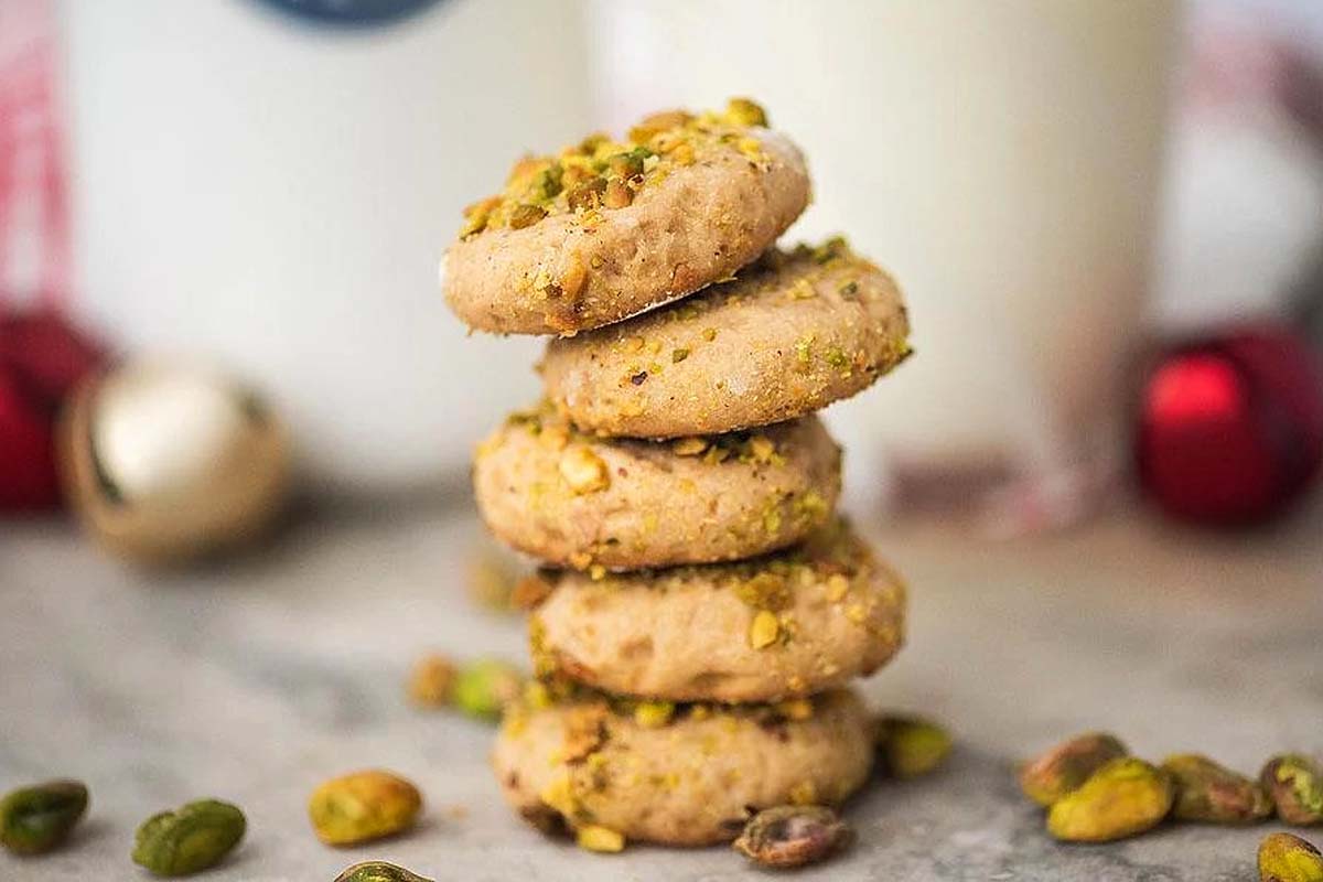 A stack of pistachio cookies next to a glass of milk, perfect for indulging in delicious pistachio recipes.