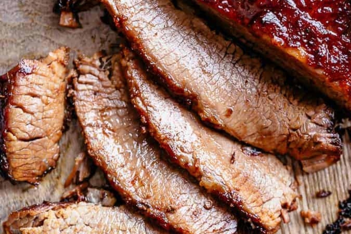 Christmas dinner featuring succulent sliced brisket with sauce served on a cutting board.