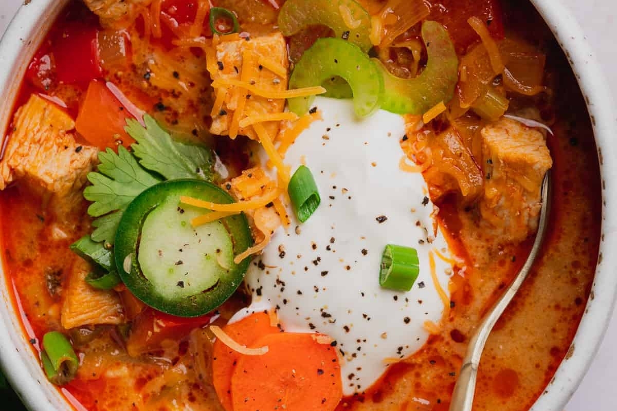 A flavorful recipe for chicken soup with vegetables, garnished with a dollop of sour cream.