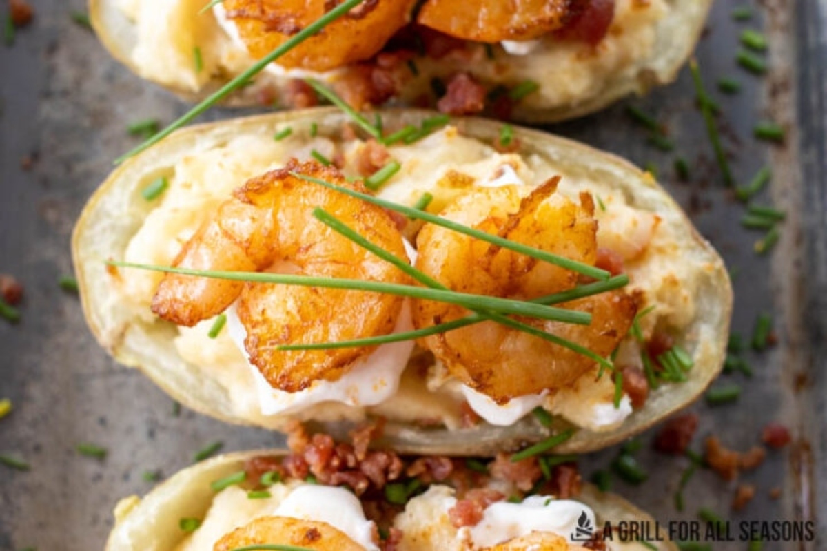 Three shrimp stuffed potatoes on a baking sheet.