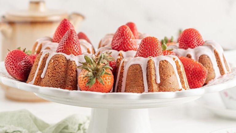A bundt cake with strawberries and icing on a white plate.