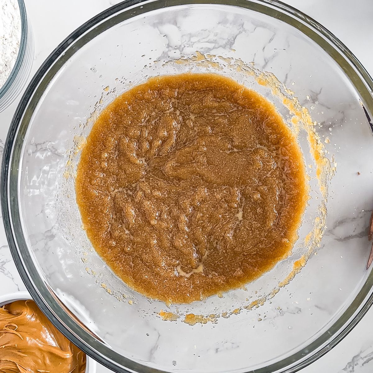 The ingredients for a peanut butter cookie batter in a glass bowl, perfect for making peanut butter chocolate chip bars.