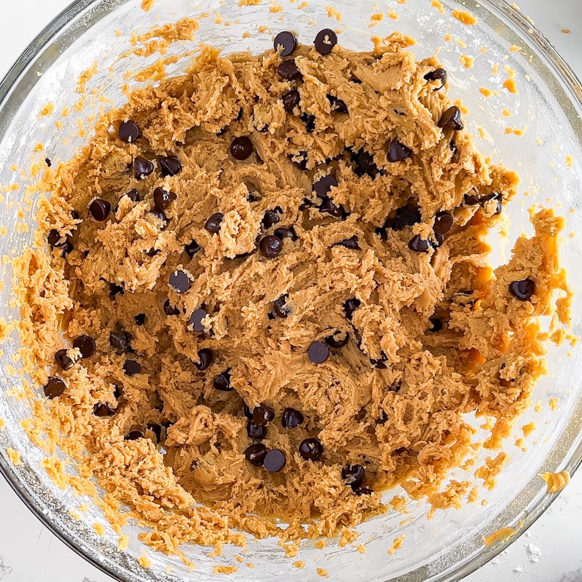 Peanut butter chocolate chip cookie dough in a glass bowl.