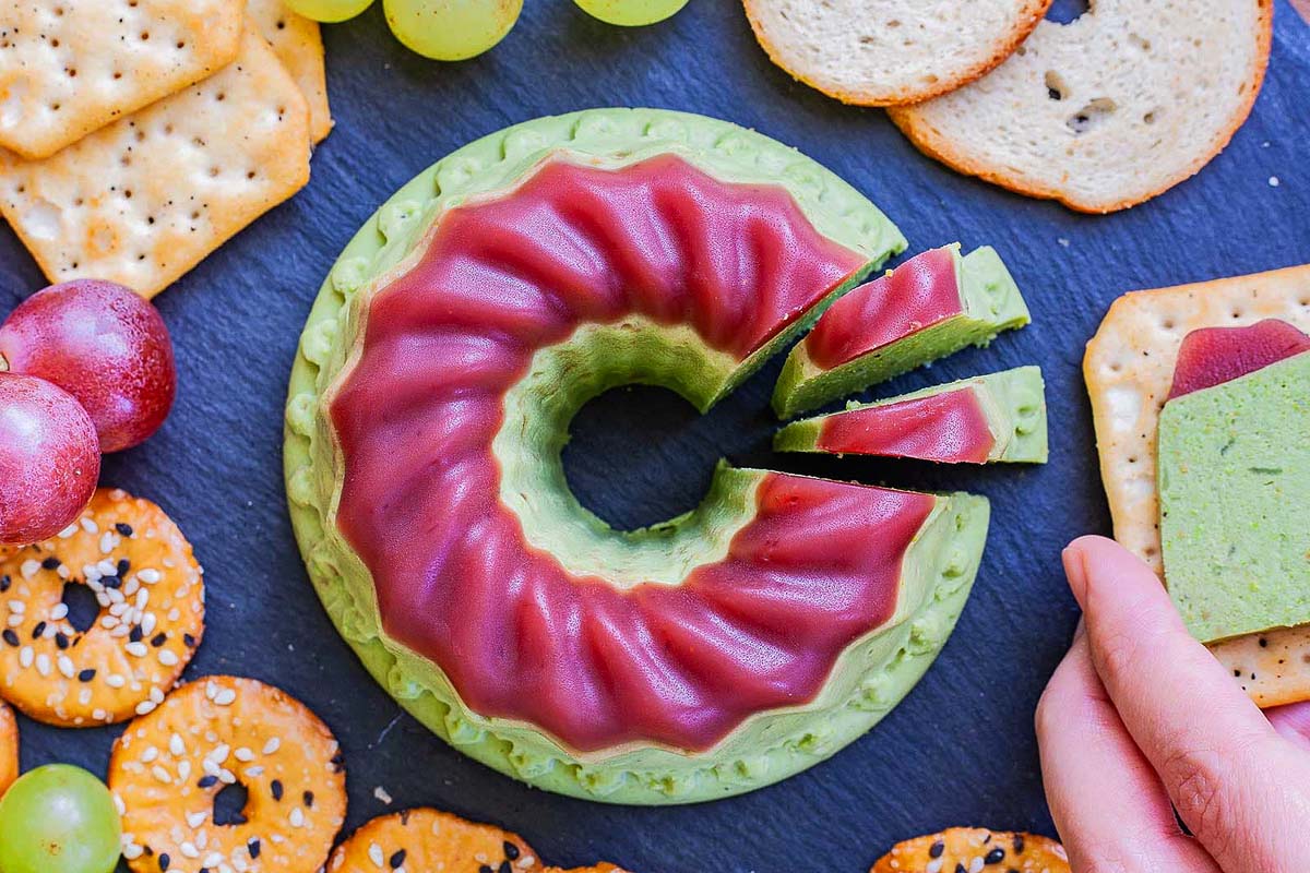 A festive slice of cheese adorned with grapes and surrounded by savory crackers.