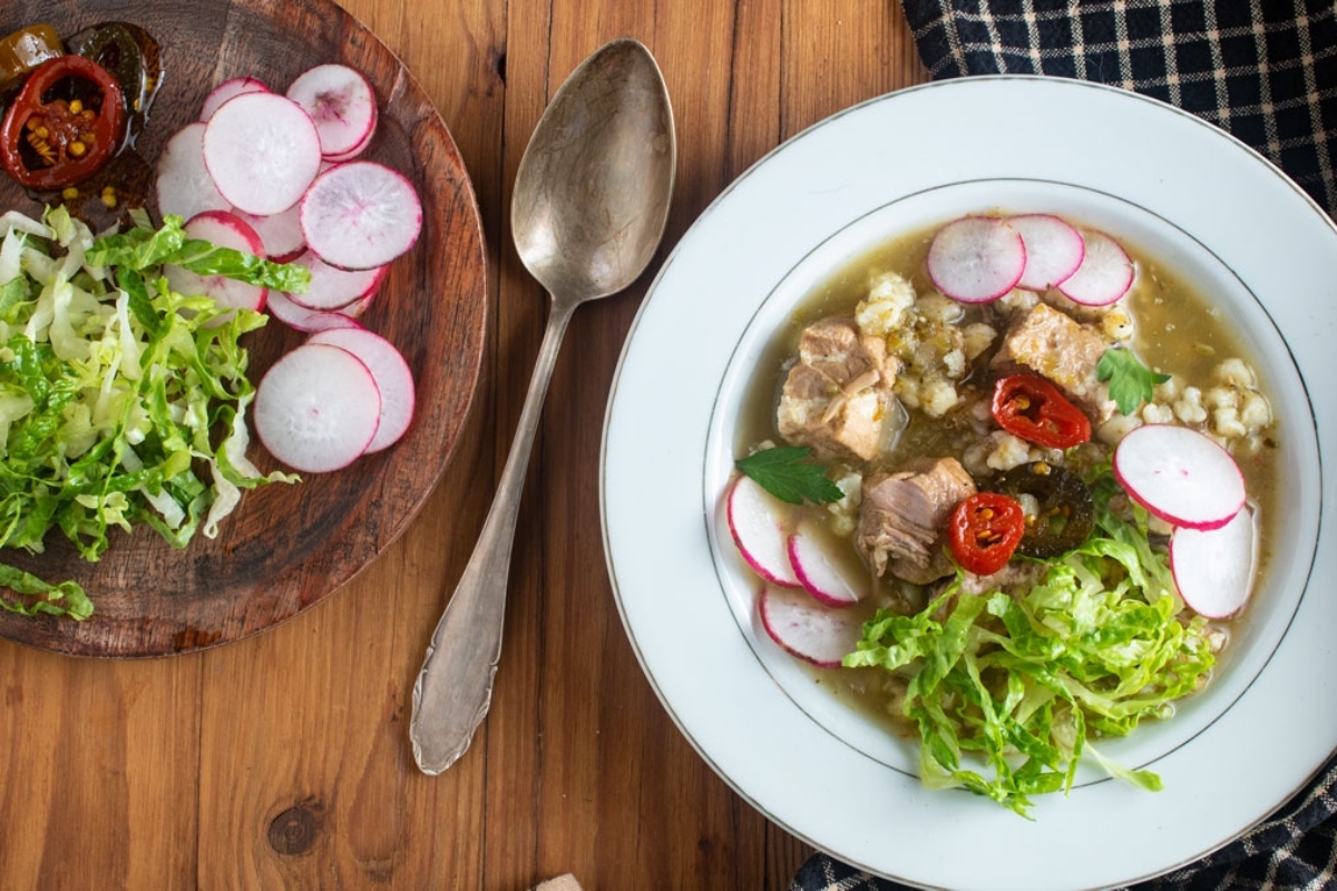 A bowl of Winter soup with meat on a wooden table.