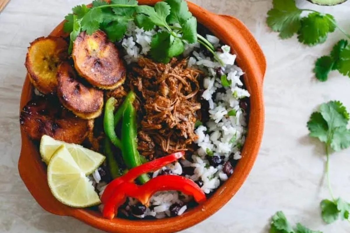 A bowl of black beans and rice with a lime on top.