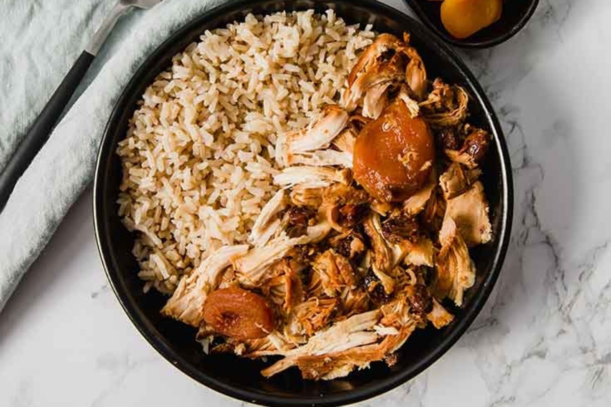 A black bowl with rice and chicken in it.