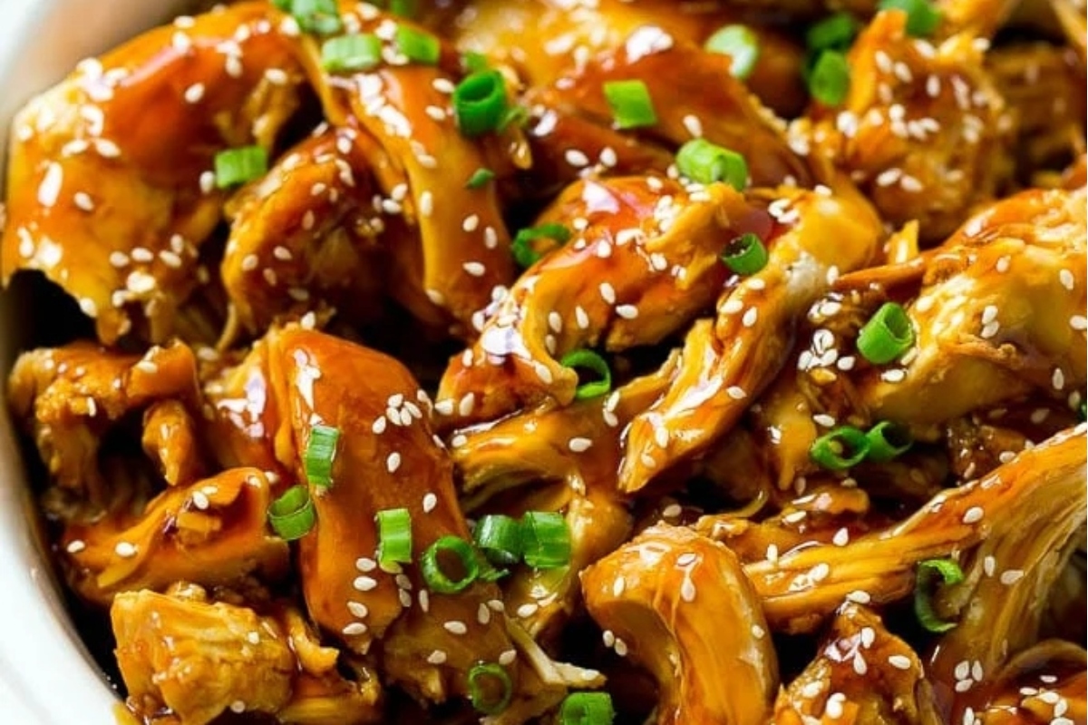 Asian chicken in a white bowl with sesame seeds.