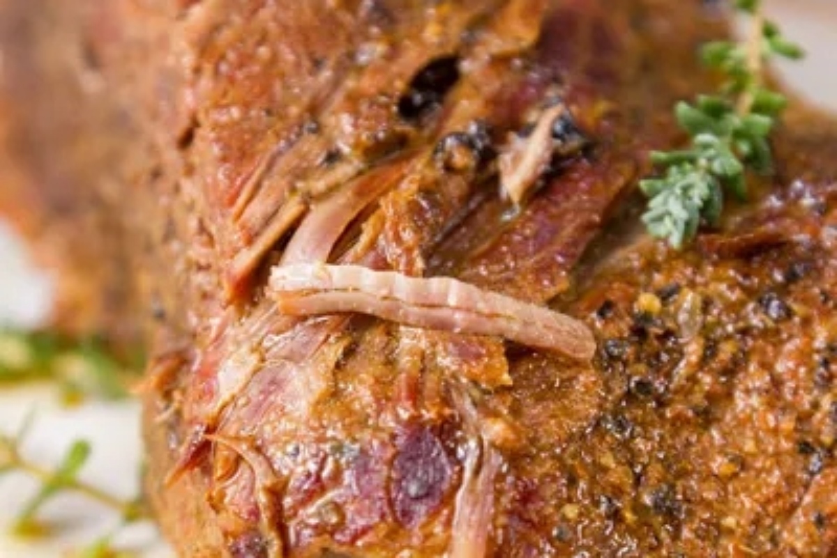 A close up of a roast with herbs on it.