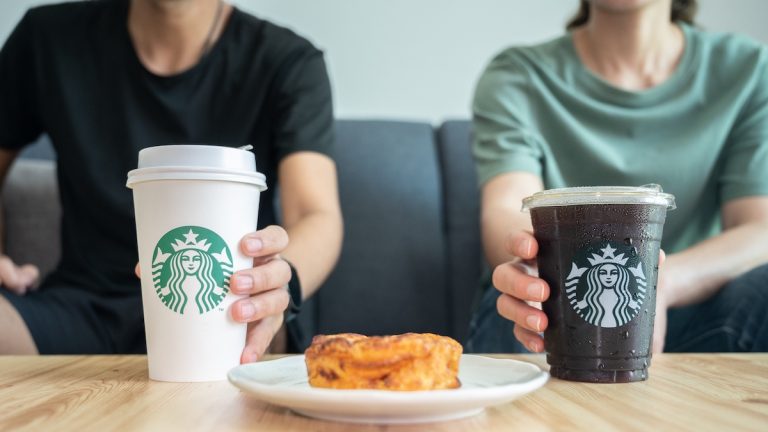 Two people enjoying Starbucks coffee and pastries from the breakfast menu.