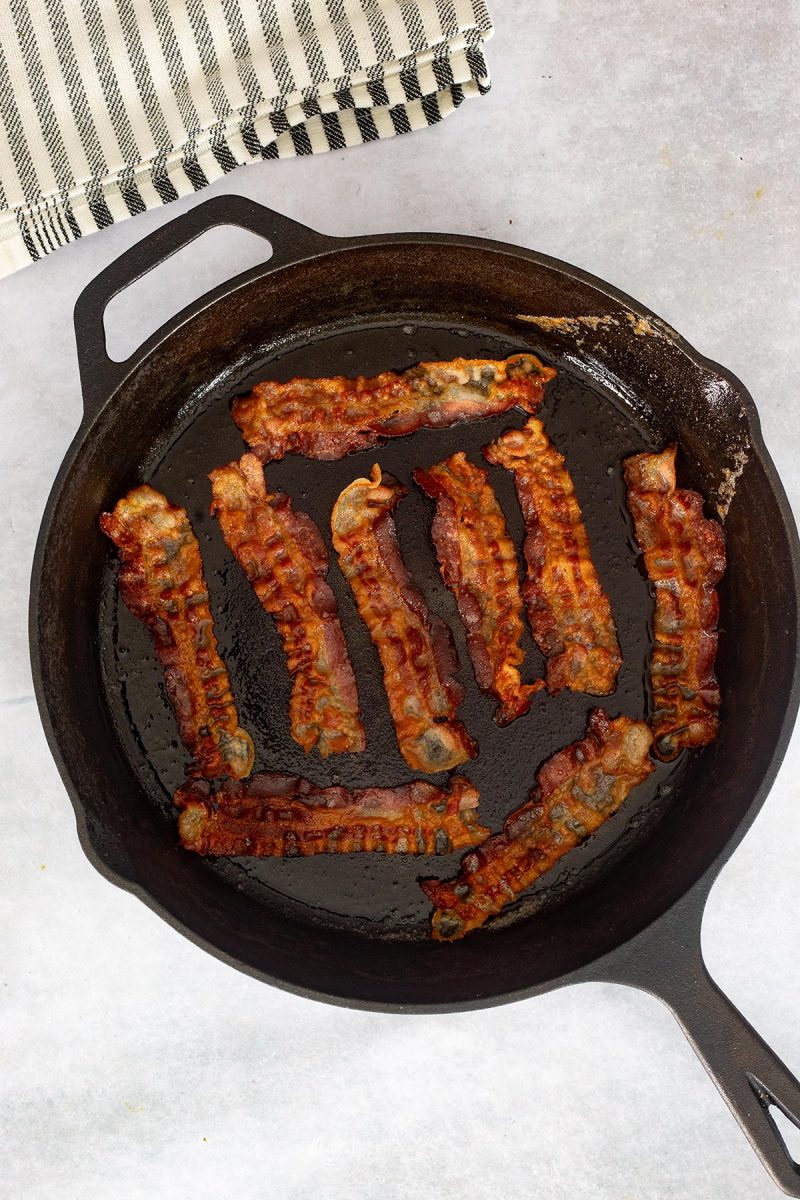 Loaded mac and cheese with bacon in a skillet on a white background.