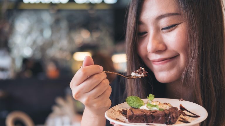 A woman indulging in a delicious chocolate brownie in a restaurant.