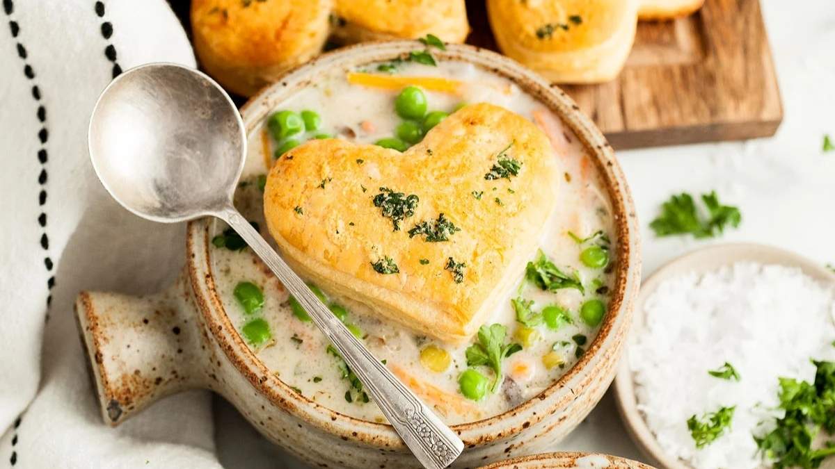 Comforting heart shaped soup recipe served in a bowl with biscuits and peas.