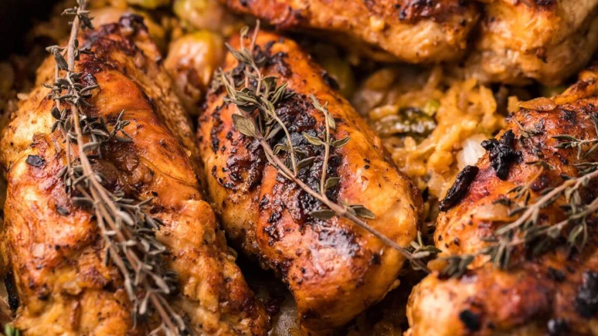 Chicken breasts with sprigs of thyme in a skillet.