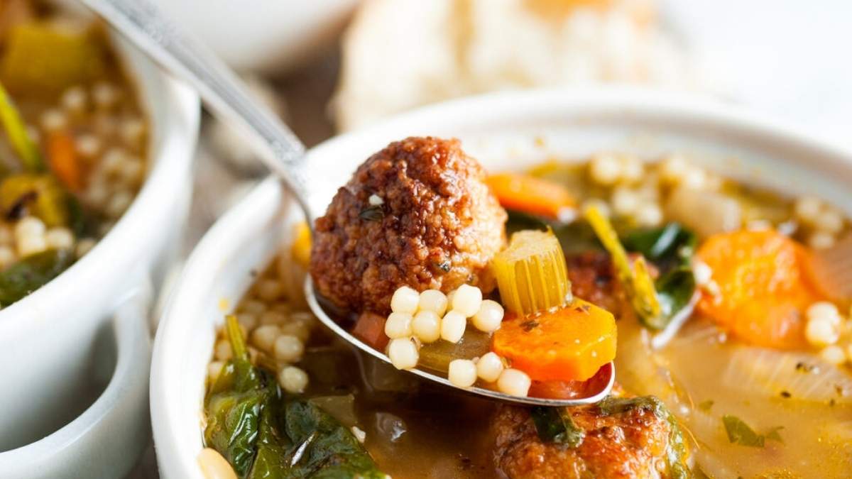 A shared bowl of soup with meatballs and vegetables.
