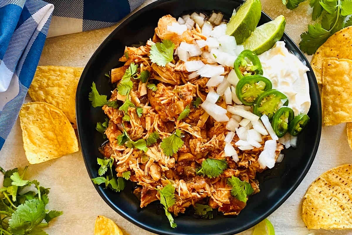 A black bowl with shredded chicken and tortilla chips.