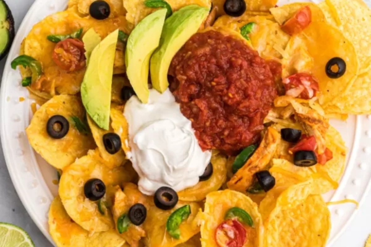 A plate of nachos with sour cream and avocado.