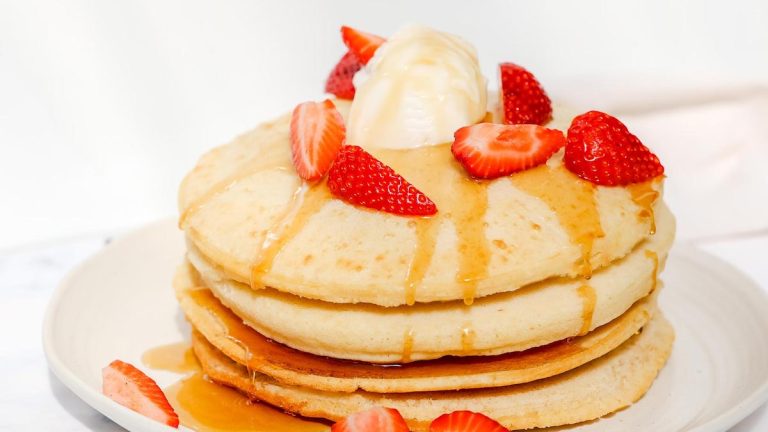 Air fryer pancakes topped with strawberries and syrup.