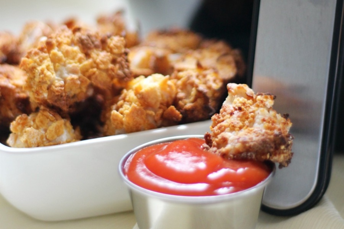 Fried chicken nuggets in a bowl with ketchup.