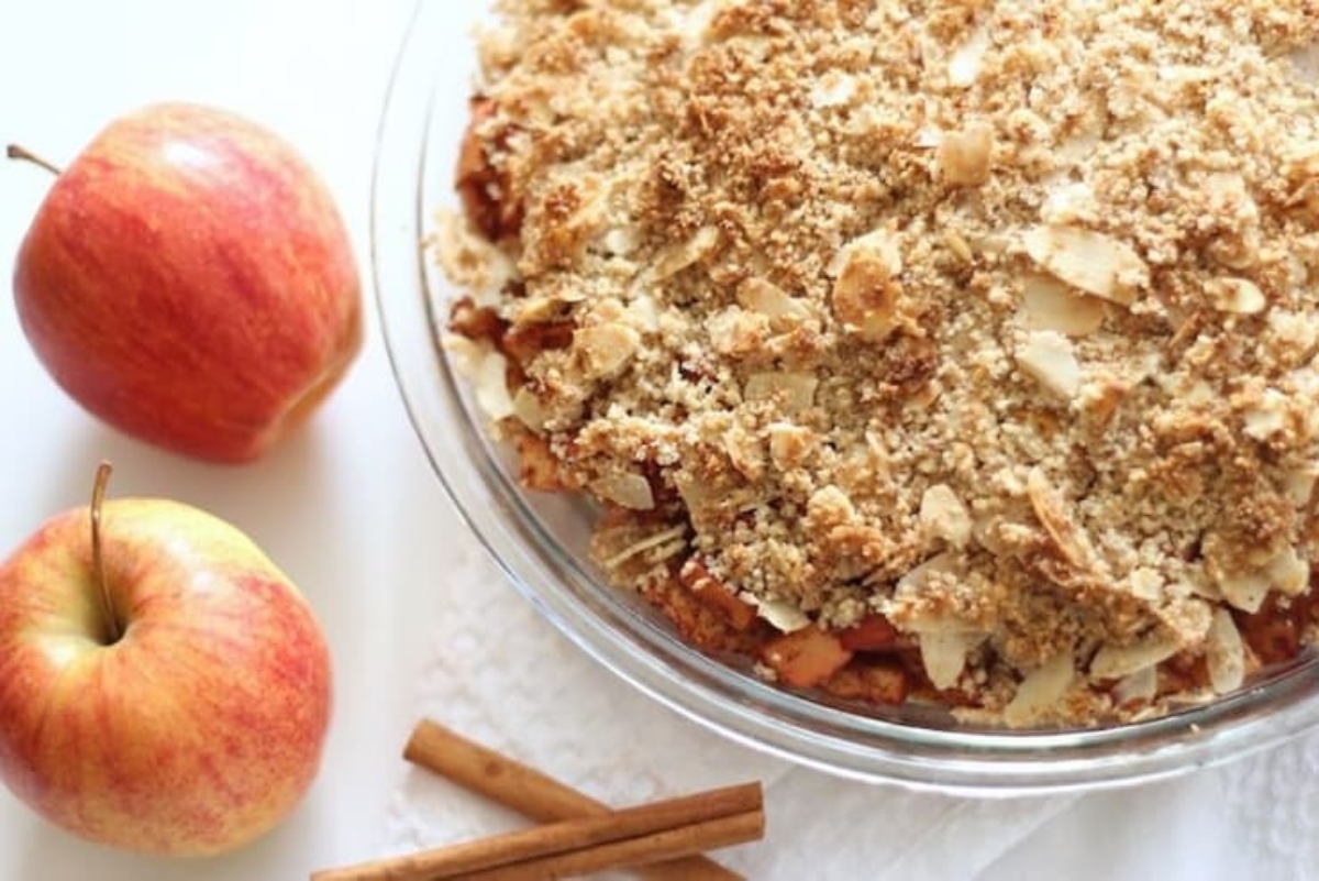 A dish with apples and cinnamon next to it.