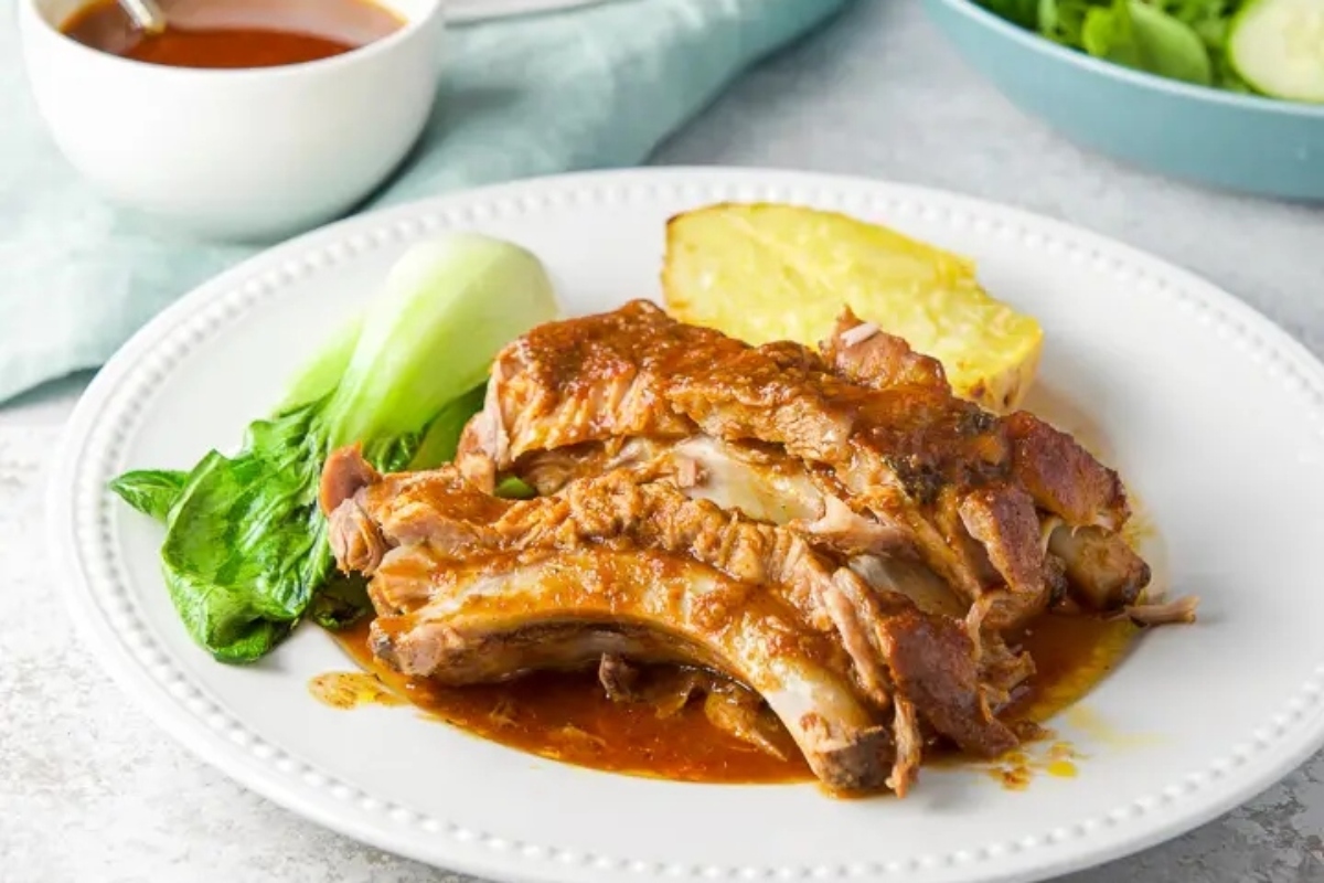A plate of pork ribs with sauce on it.
