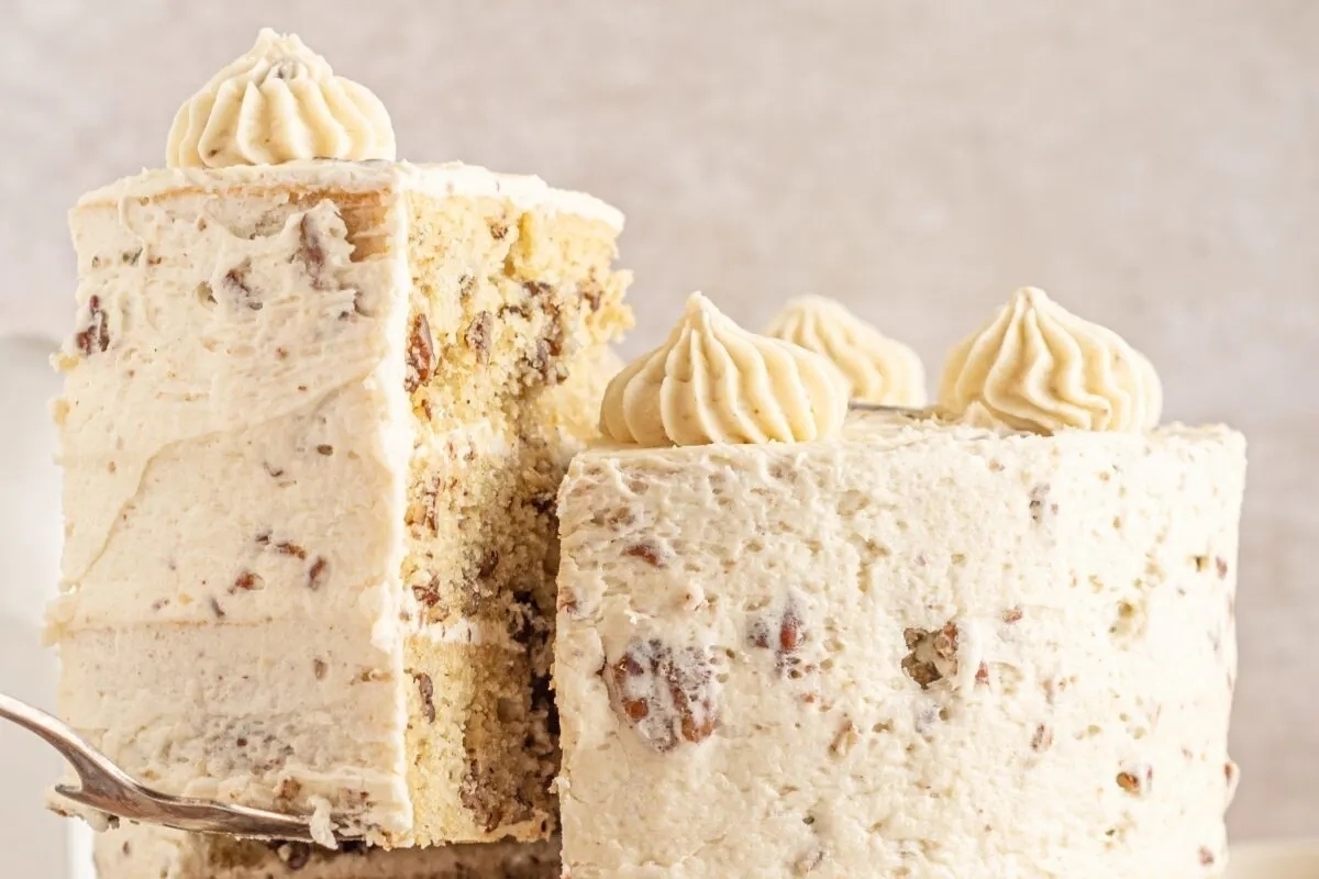 A slice of cake is being taken out of a cake stand.