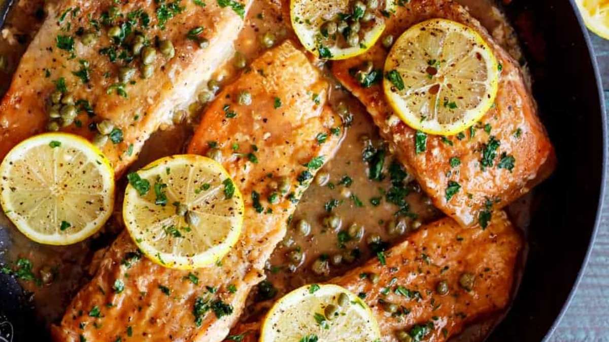 Salmon fillets in a skillet with lemon slices.
