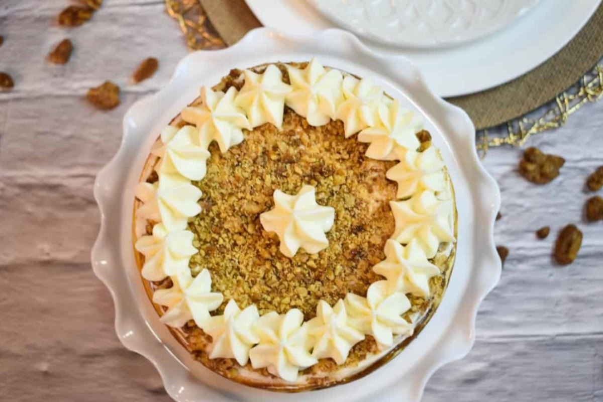 A carrot cake with whipped cream and pecans on a plate.