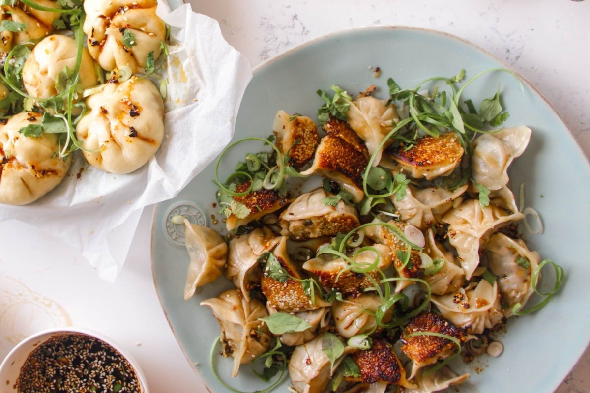 A plate of dumplings and a bowl of greens.