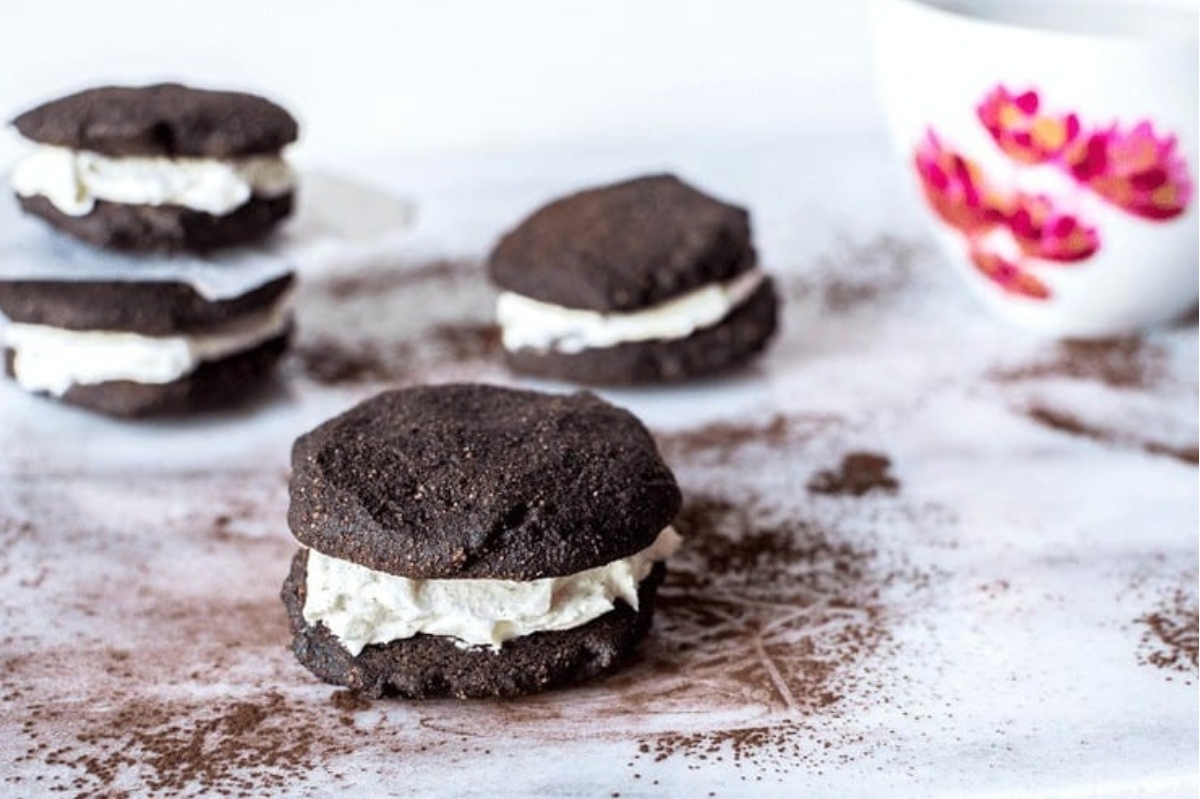 Chocolate oreo cookies on a white plate with a cup of coffee.