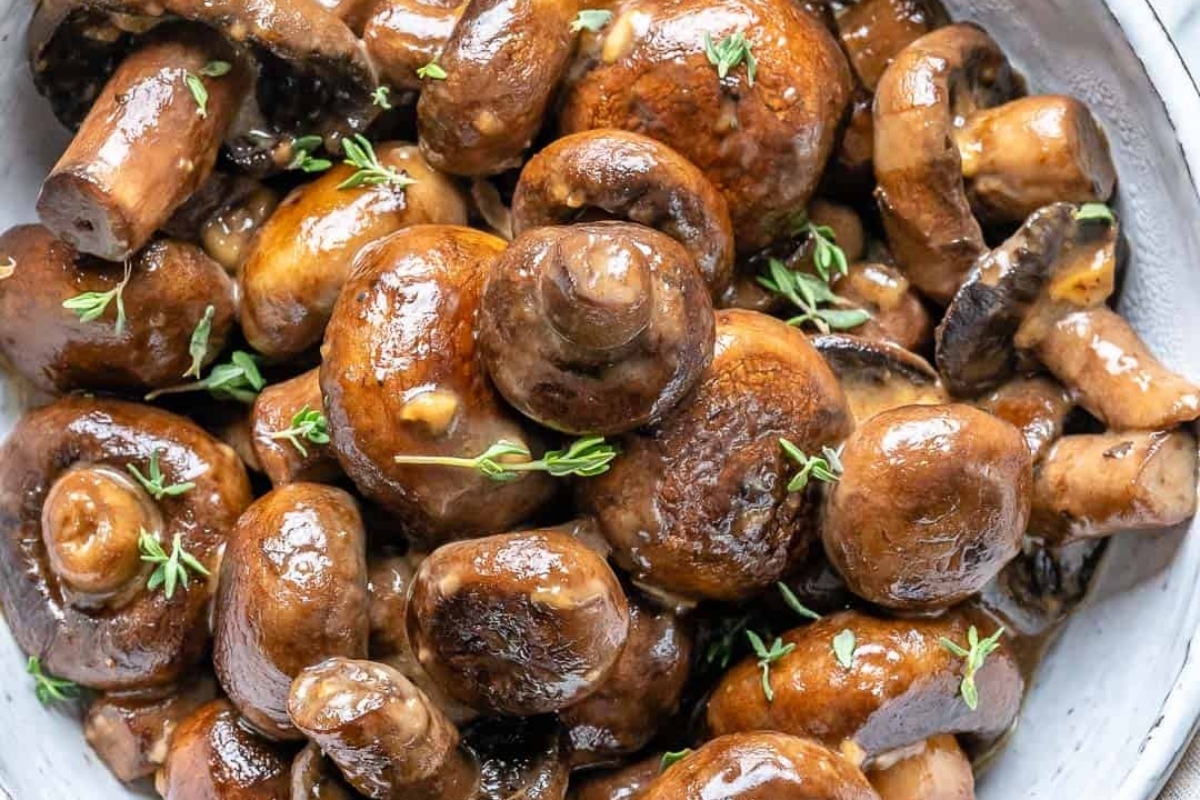 Mushrooms in a white bowl with thyme.