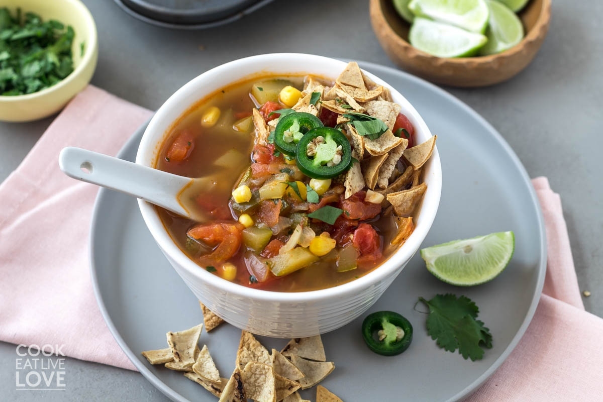 A bowl of corn tortilla soup with lime and tortilla chips.