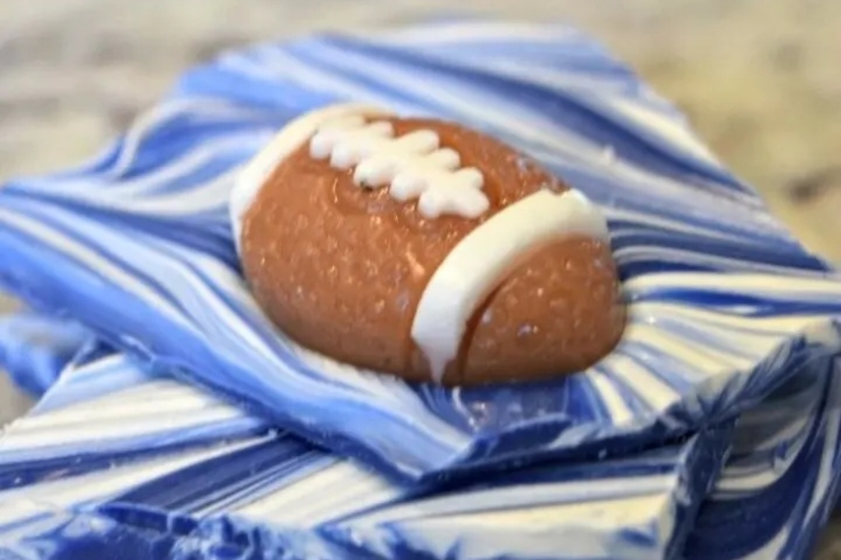 A football shaped chocolate bar is sitting on top of a blue and white marble.