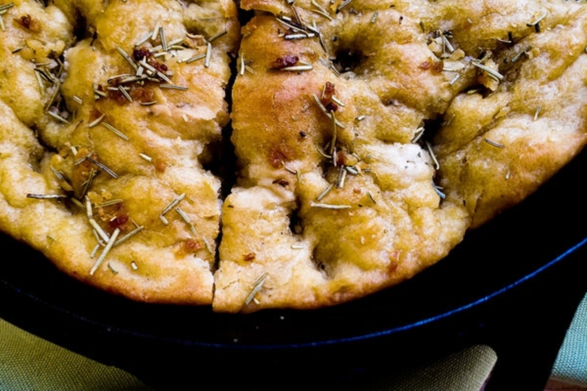 A loaf of bread with rosemary in a cast iron skillet.