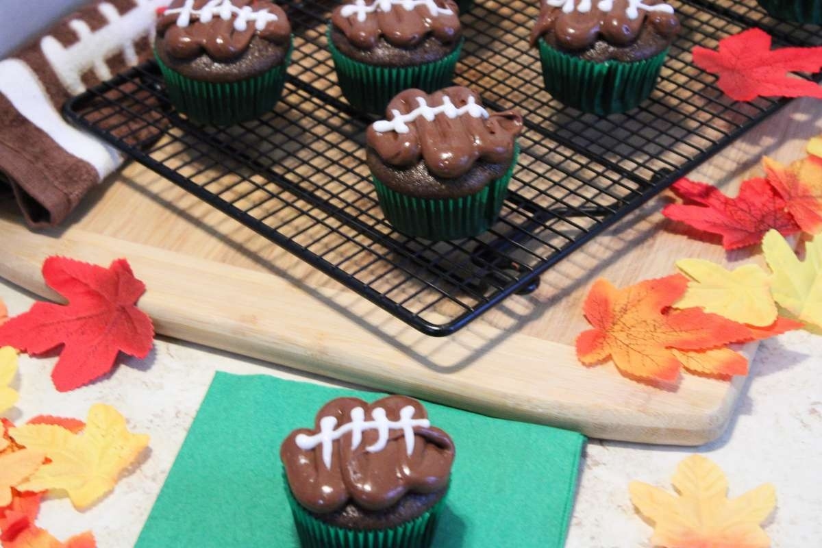 Chocolate football cupcakes on a cooling rack.