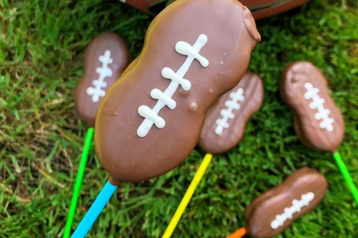 Chocolate football shaped lollipops on a stick.