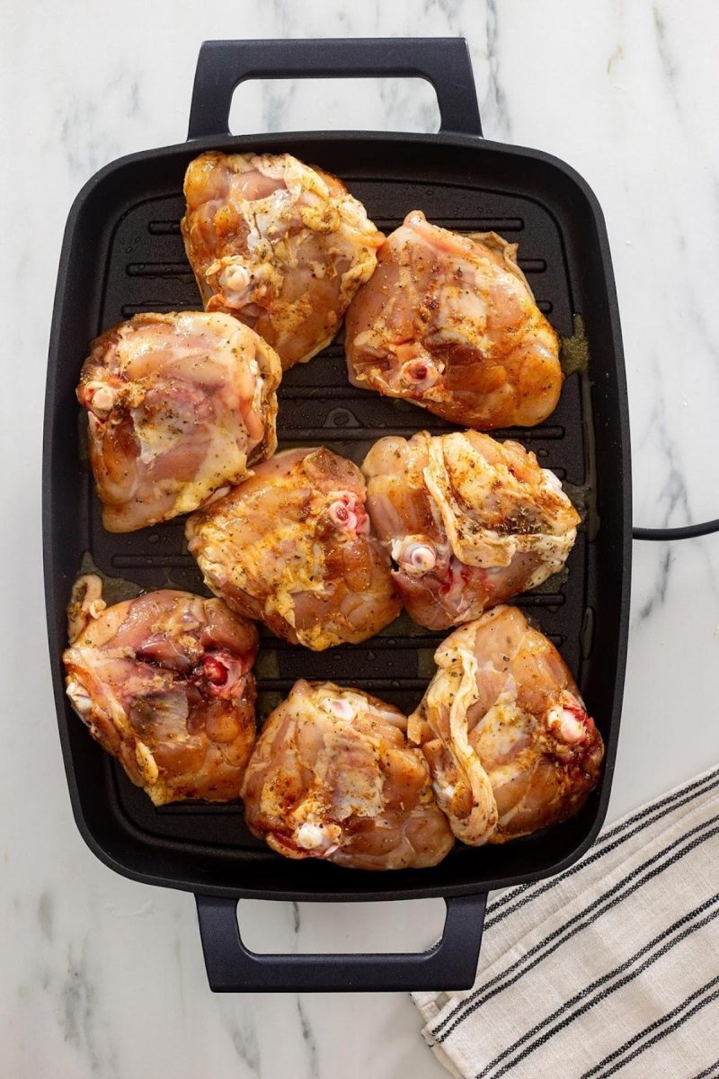 Chicken thighs grilling on a countertop.