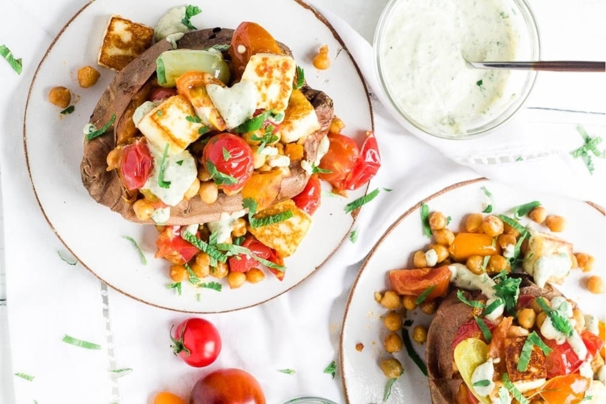 A plate of roasted sweet potatoes with chickpeas and tzatziki sauce.