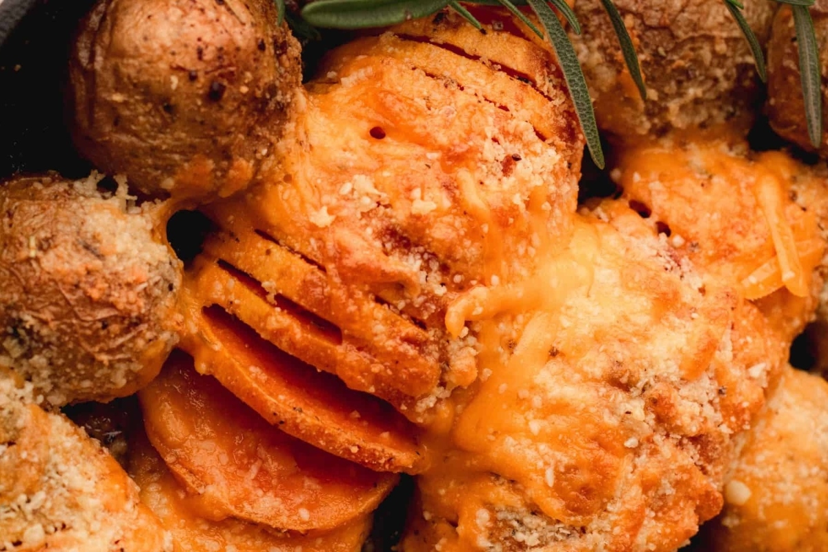 Roasted sweet potatoes in a skillet with sprigs of rosemary.