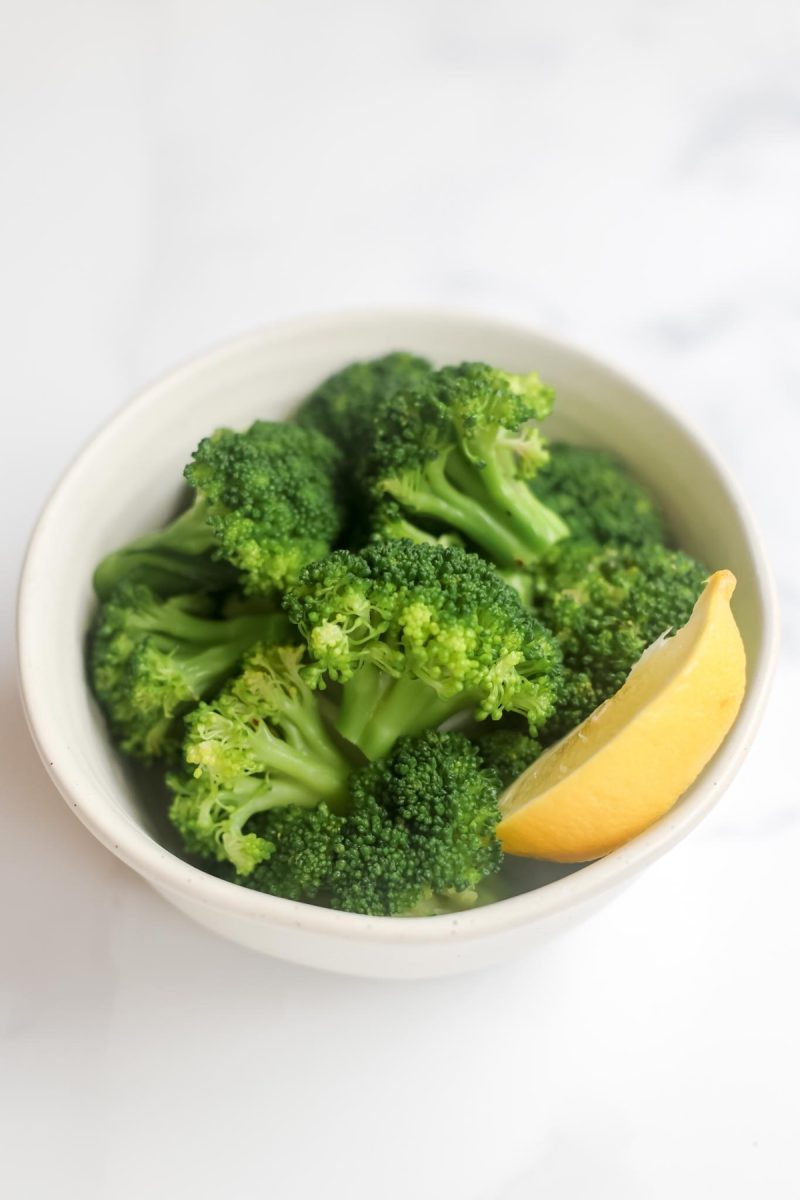 A bowl of broccoli with a slice of lemon.