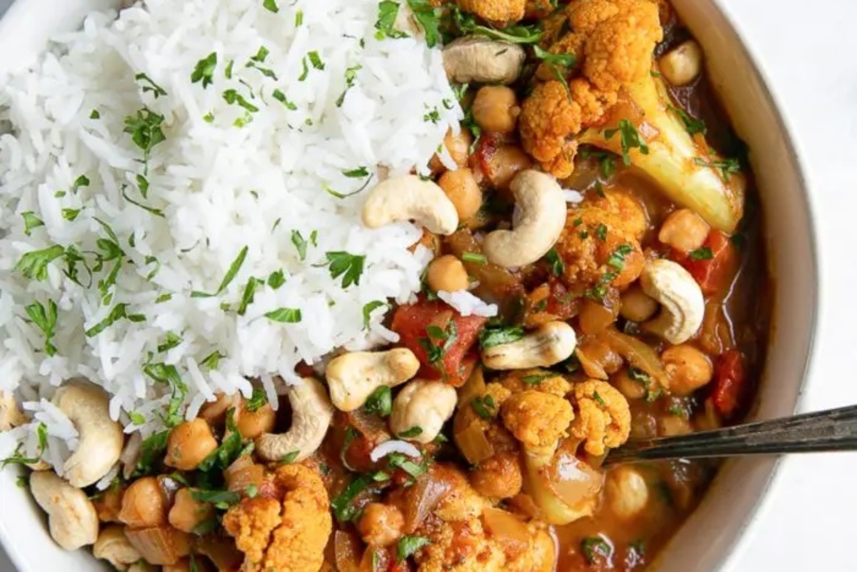A bowl of cauliflower curry with rice and cashews.